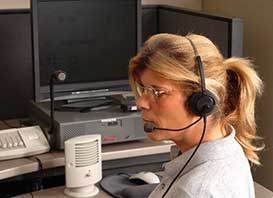 Una operadora del servicio de emergencia con audífonos, frente a un computador