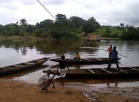 Photo of Guinea people standing on boats in a river.