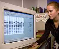 Photo of woman examining DNA readout on a computer monitor.