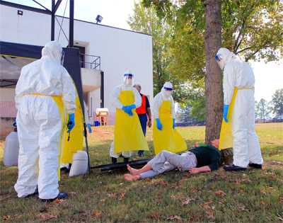 A group of students evaluates how to move a “patient” into the mock ETU at CDC’s training course in Anniston, Alabama.