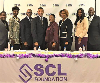 	Eight members of the Southern Christian Leadership Foundation smiling in front of a banner