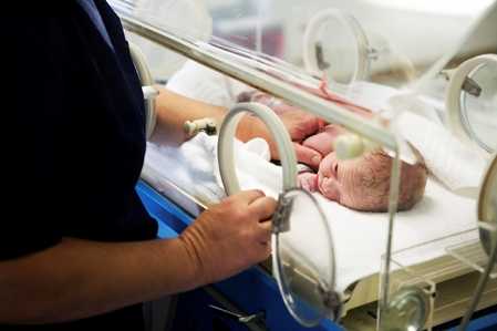 image of a premature infant being cared for by a healthcare assistant