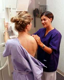 Photo of a technician preparing a woman to get a mammogram