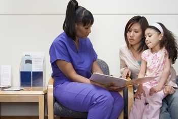 Photo of a nurse talking to a mother and her daughter