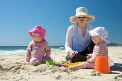 Foto de una madre y sus dos niños pequeños en la playa