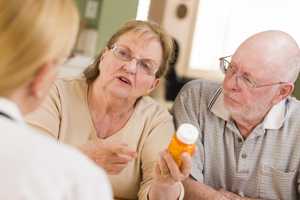 Photo of a caregiver asking a doctor a question about a cancer patient's medication