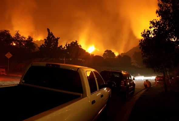 Coches a lo largo de la ruta de evacuación de incendios forestales. Wildfire en el fondo.