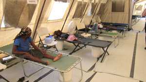 	People laying down on cots in a makeshift treatment facility in Haiti.