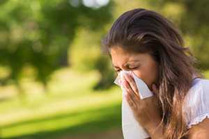 Woman blowing nose with tissue - Allergy