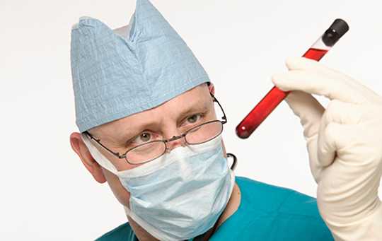man in lab mask holding a test tube