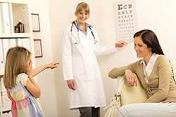	a child looking at an eye chart with her mom