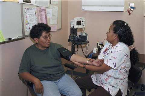 Photo of an Alaska Native woman having her blood pressure taken by a nurse.