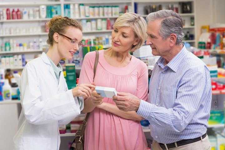 A pharmacist talking to two customers about a medication.