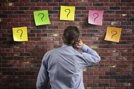 	Man staring at brick wall with five question marks on it