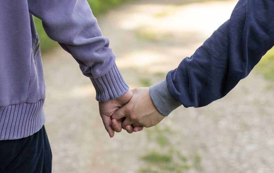 two people holding hands outdoors