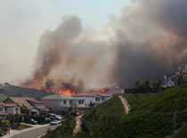 Photo of wildfire burning behind a suburban neighborhood.