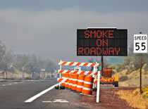 Photo of a road sign warning drivers of smoke on the highway.
