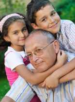 Photo of an elderly man being hugged by two children.