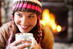 	Young Woman Holding Mug of Hot Cocoa Near Fireplace