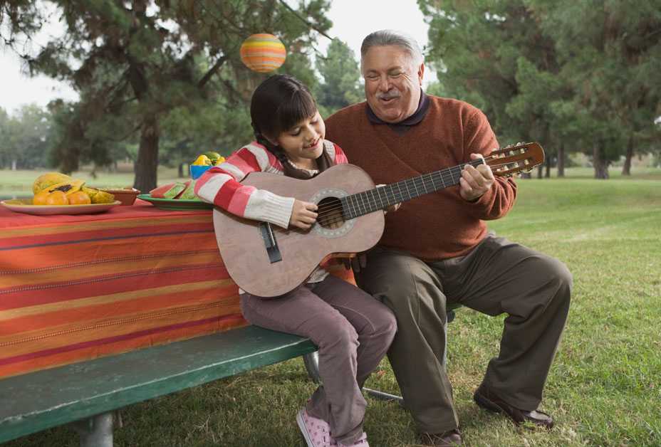 Grandfather and granddaughter playing guitar