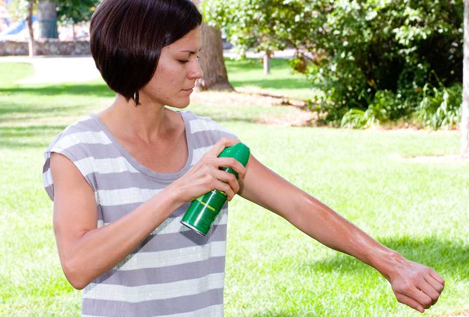 Woman spraying on insect repellent