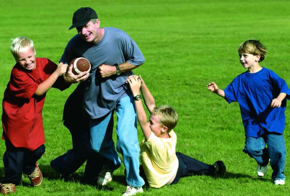 Father playing football with three boys