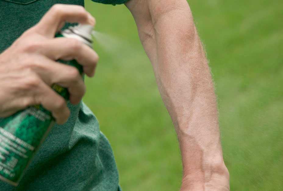 Man spraying insect repellent on arm