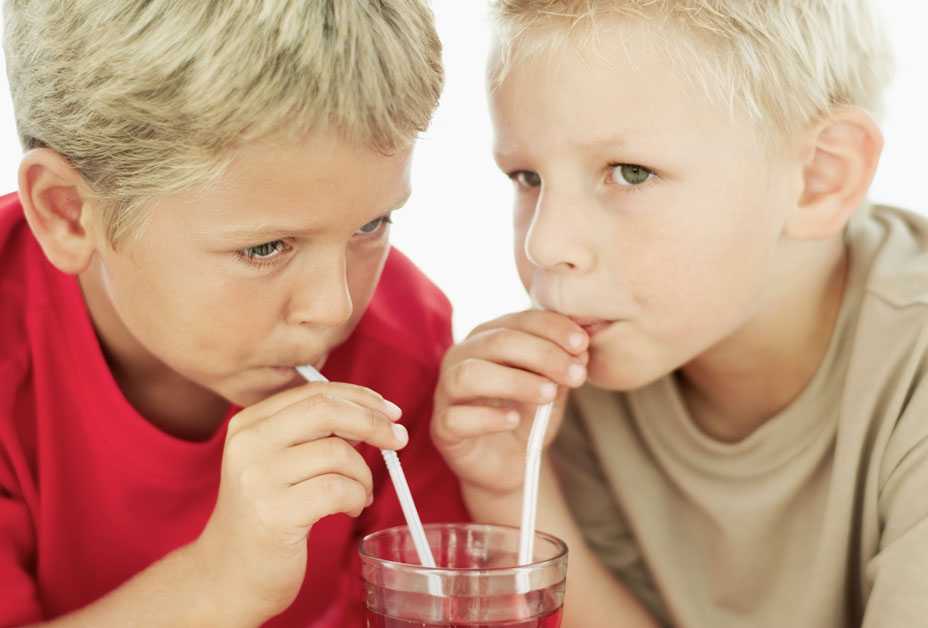 Two boys drinking out of same glass