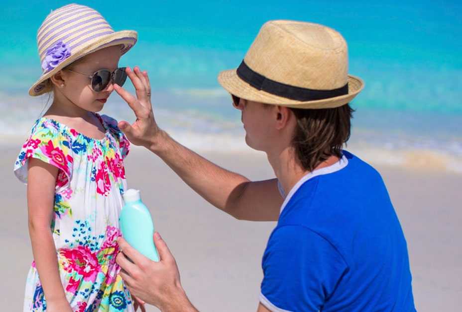 Father applying sunscreen to daughter