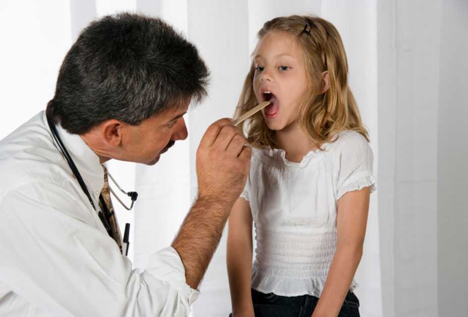 Doctor examing young girl's throat