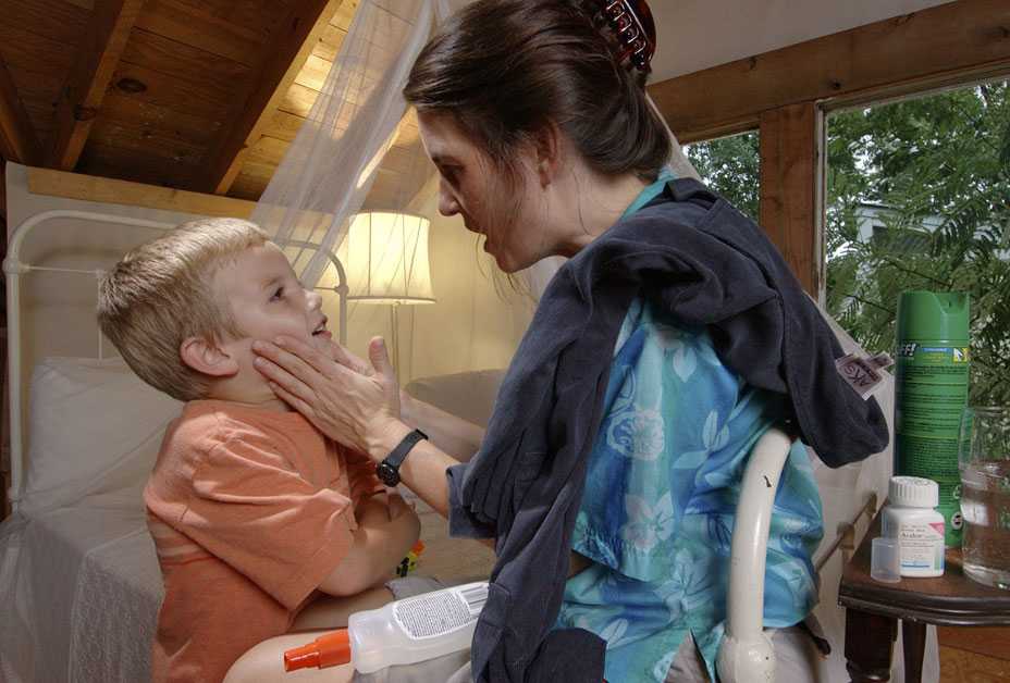 Mother applying repellent to son