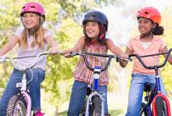 three girls wearing helmets and riding bicycles