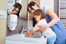 Mother helping daughter wash hands