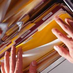 Hands thumbing through folders in file cabinet