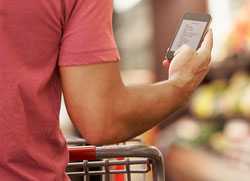 Man checking smartphone while grocery shopping