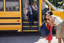 Girl hugging mother goodbye before boarding school bus