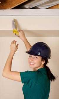 Photo: A woman applying caulk to a wall.