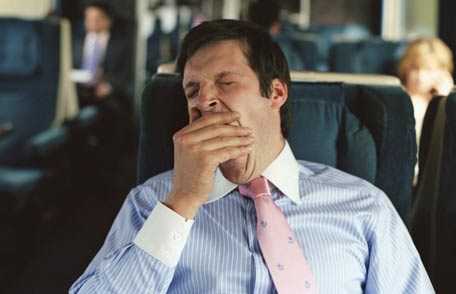 Business man yawning on commuter train