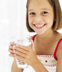 Young girl holding glass of water and smiling