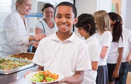 Boy holding plate of healthy food in cafeteria