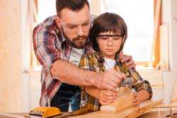 Father and son woodworking and wearing safety glasses