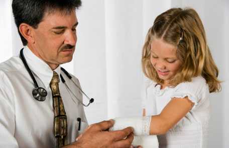 Doctor bandaging girl's arm