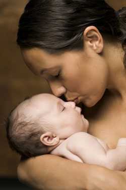 Mother kissing newborn's forehead