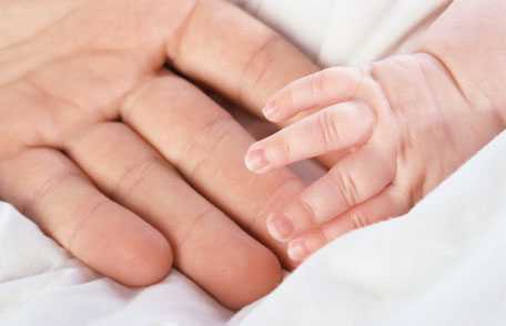 Adult hand holding baby's hand