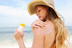 Woman putting on sun tan lotion