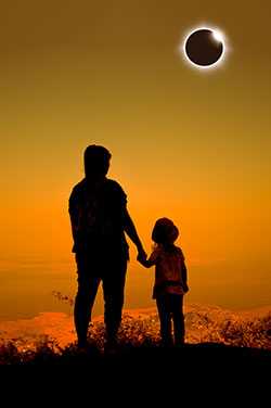 Mother holding child's hand and watching eclipse