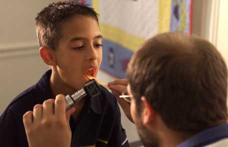 Doctor examing young boy's throat