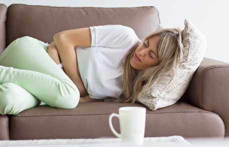 Woman lying on couch, holding stomach