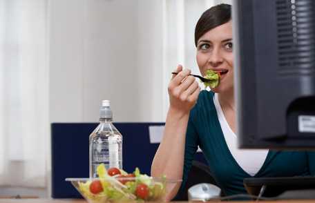 Woman at computer eating fruit salad