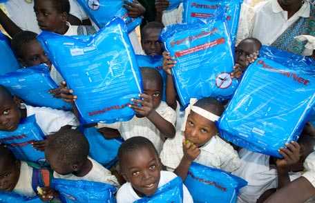 Group of children holding packages of insecticidal nets